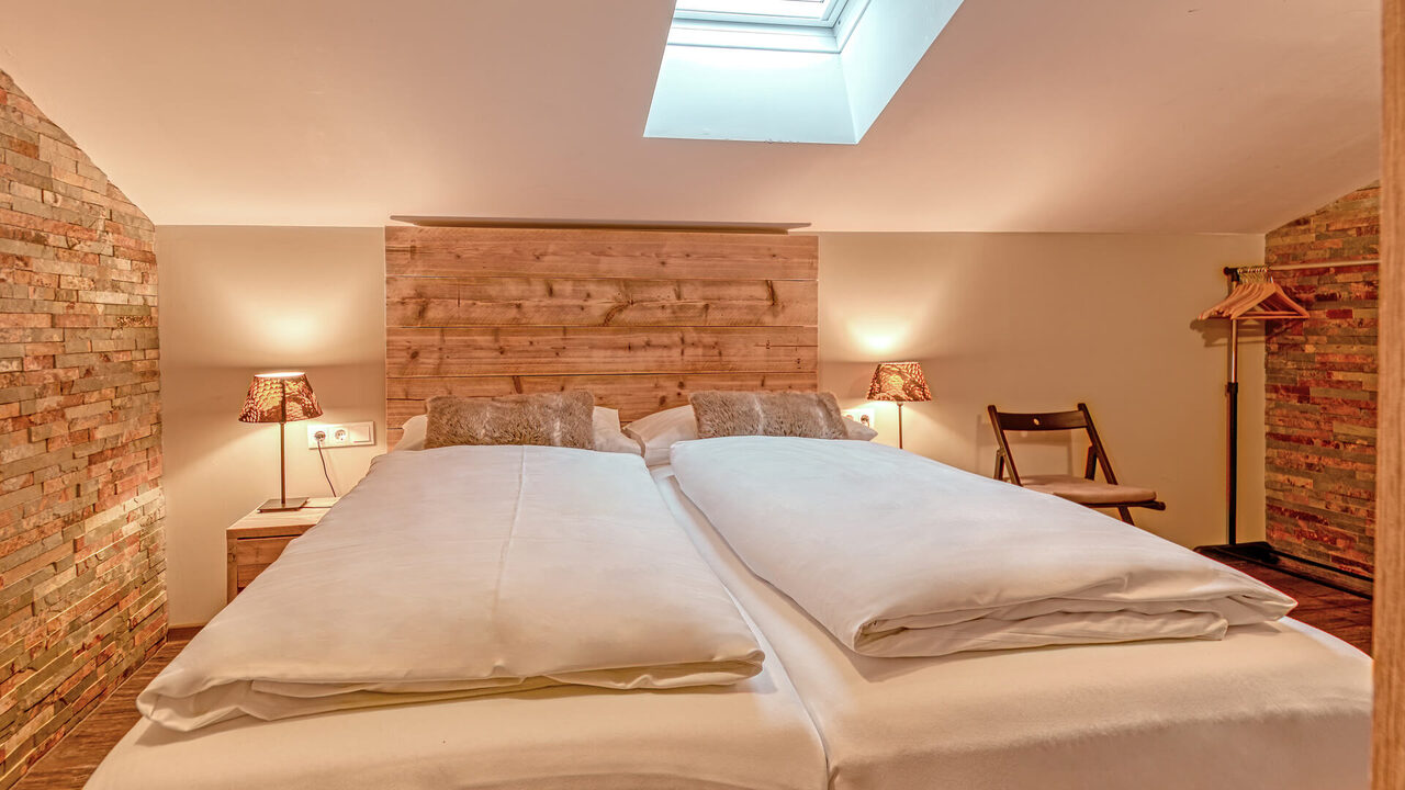 Schlafzimmer mit Doppelbett unter dem Dachfenster im Apartment Brunnach
