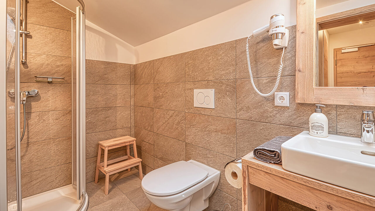 Badezimmer mit Dusche und Waschtisch im Apartment Brunnach