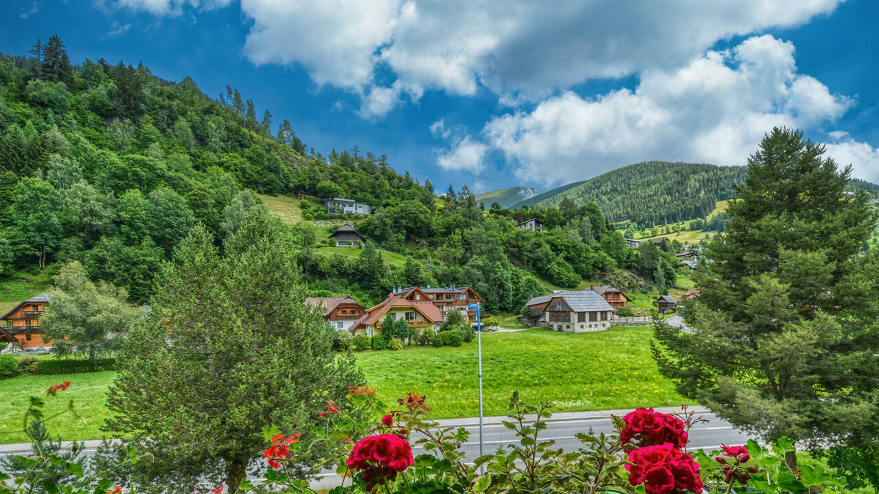 Blick vom Balkon des Apartments Brunnach auf Wiesen, Chalets und bewaldete Hügel