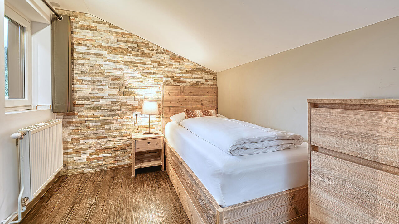 Schlafzimmer mit Einzelbett und Natursteinwand im Apartment Hirschsprung