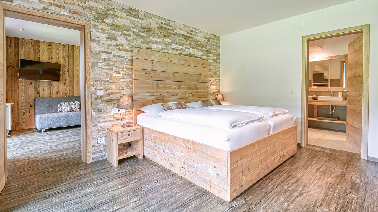 Bedroom with double bed and a view through to the living room in the Nockalm apartment