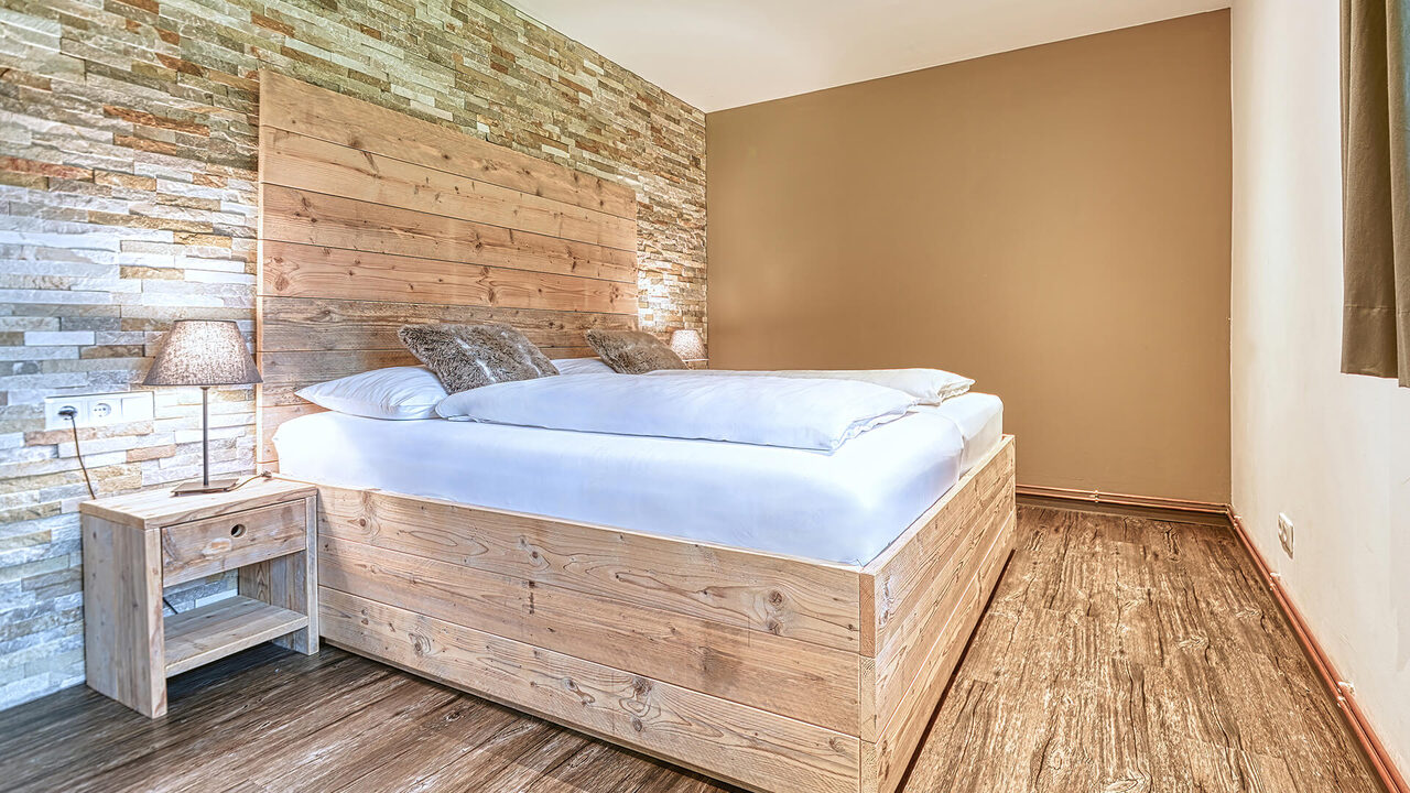 Schlafzimmer mit Doppelbett und Natursteinwand im Apartment Panorama