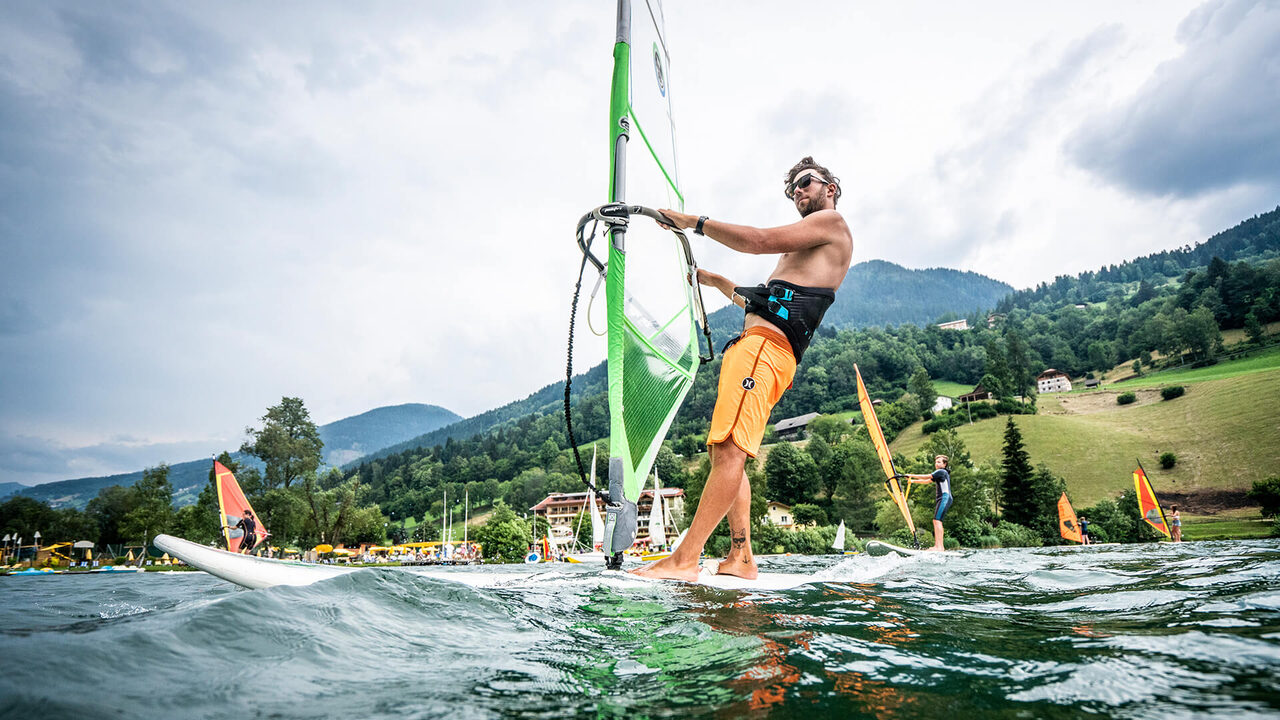 Windsurfista su un lago con le montagne sullo sfondo