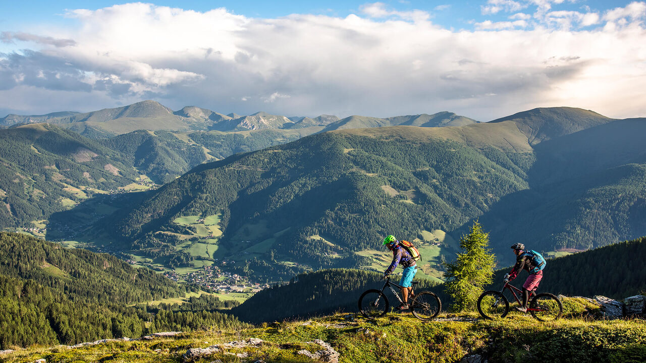 Due mountain biker su un prato alpino alto sopra la valle