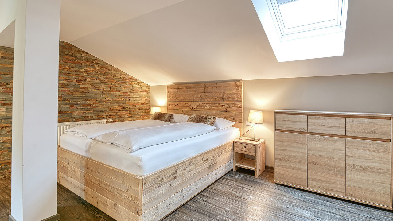 Schlafzimmer mit Doppelbett unter dem Dachfenster im Apartment Wiesernock