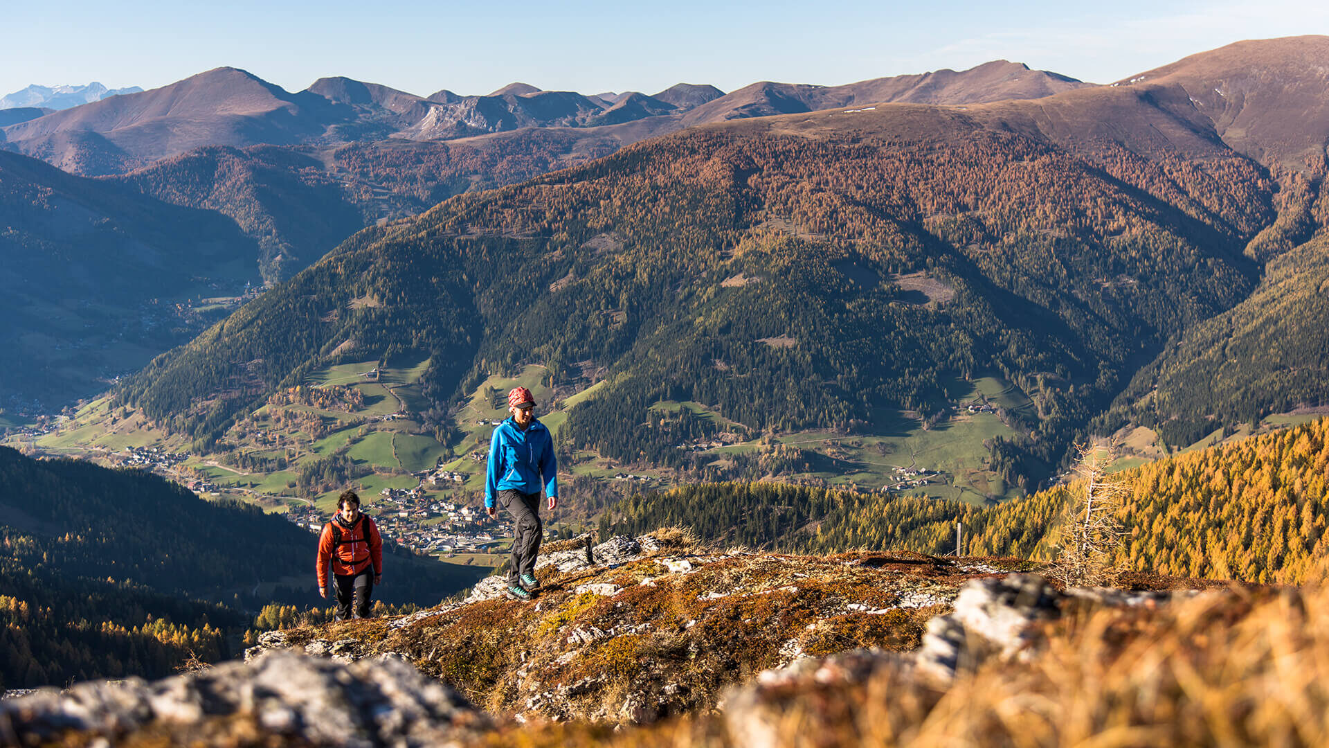 Wanderer auf einem Felsgrat über einem herbstlichen Tal