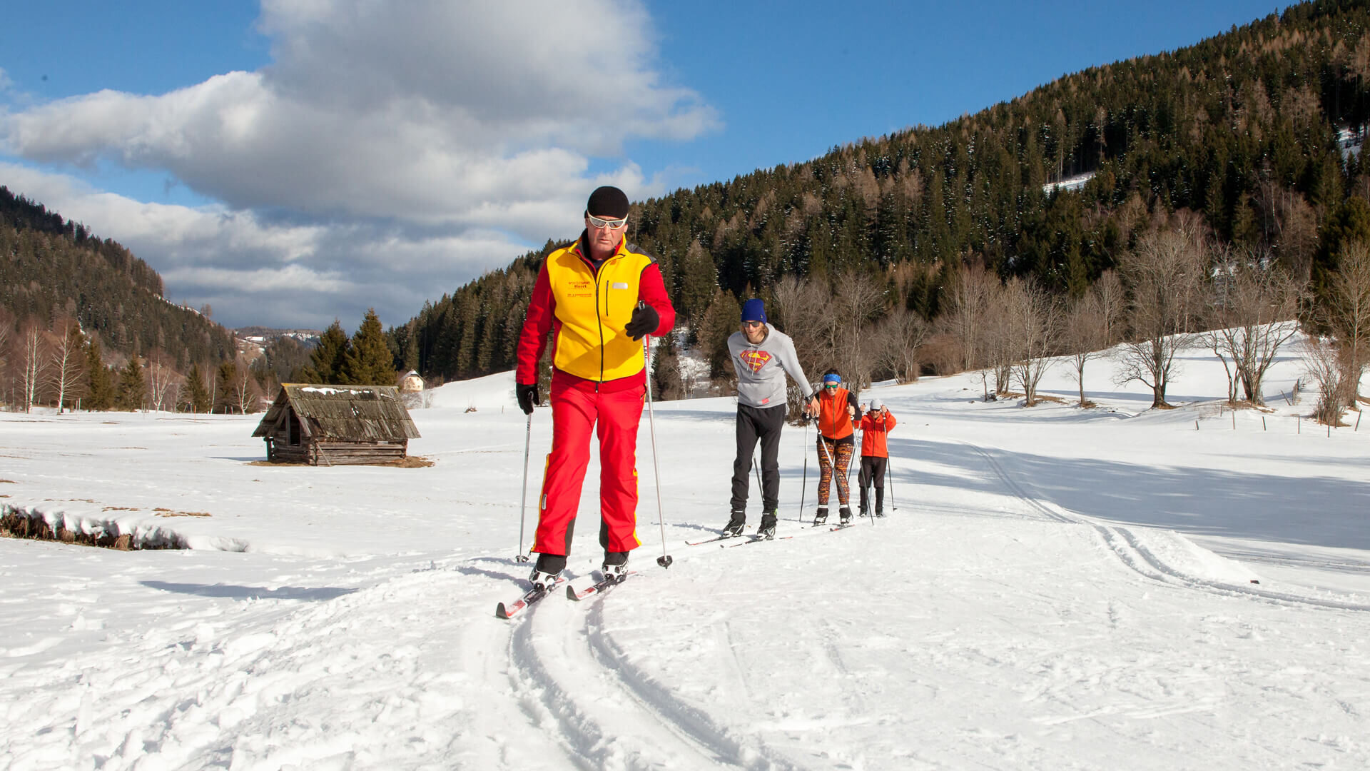 Fondisti sulla pista sotto pendii boscosi
